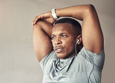 Buy stock photo Shot of a sporty young man stretching his arms while exercising at home