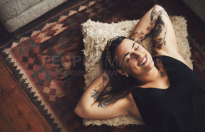 Buy stock photo Shot of a young woman relaxing on the floor of her living room at home
