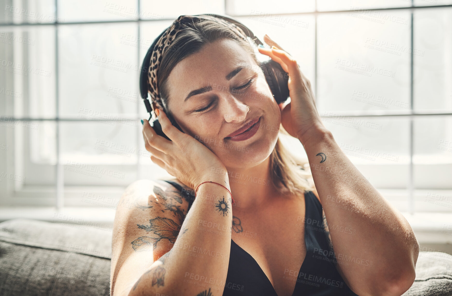 Buy stock photo Shot of a young woman using headphones on the sofa at home