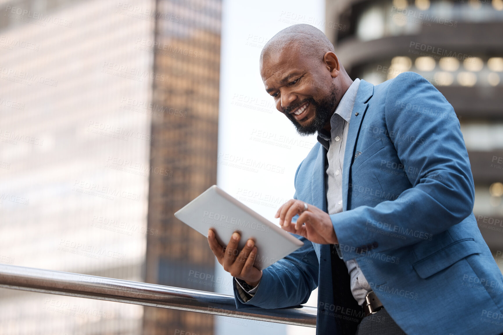 Buy stock photo Shot of a mature businessman using a digital tablet while standing on a balcony outside an office