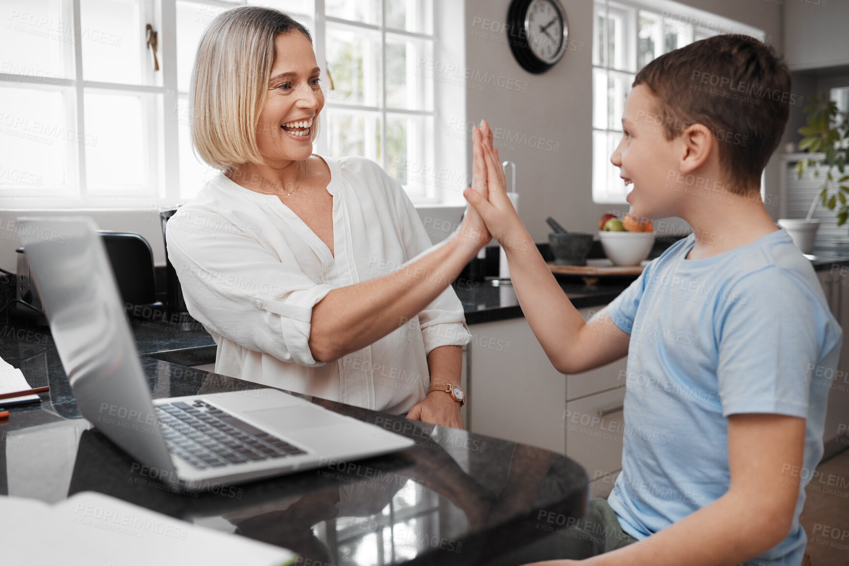 Buy stock photo Shot of a young mother and her son high fiving while home schooling
