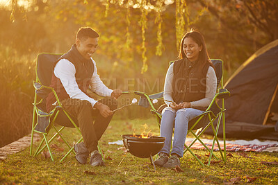 Buy stock photo Shot of a couple roasting marshmellows while camping