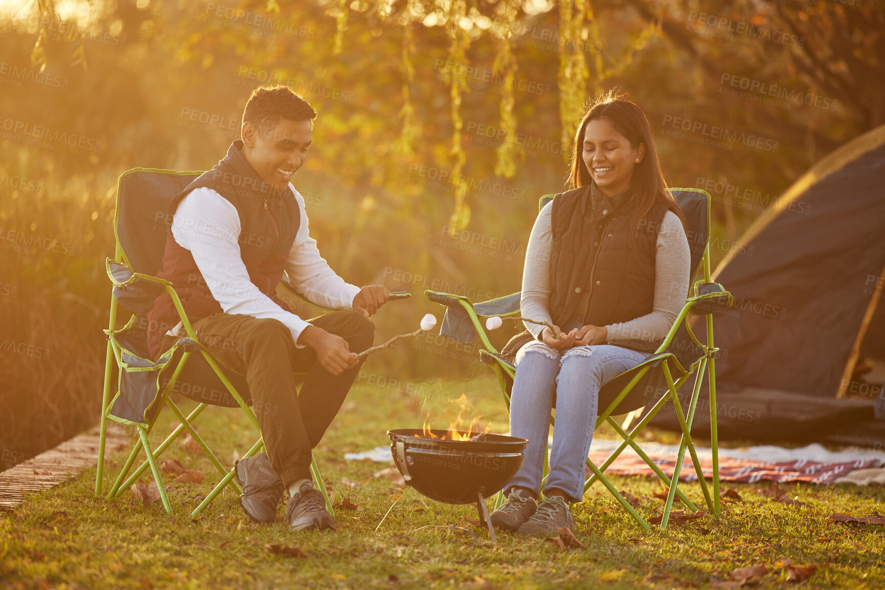 Buy stock photo Shot of a couple roasting marshmellows while camping