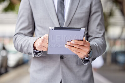 Buy stock photo Cropped shot of an unrecognizable businessman standing and using a digital tablet in the city