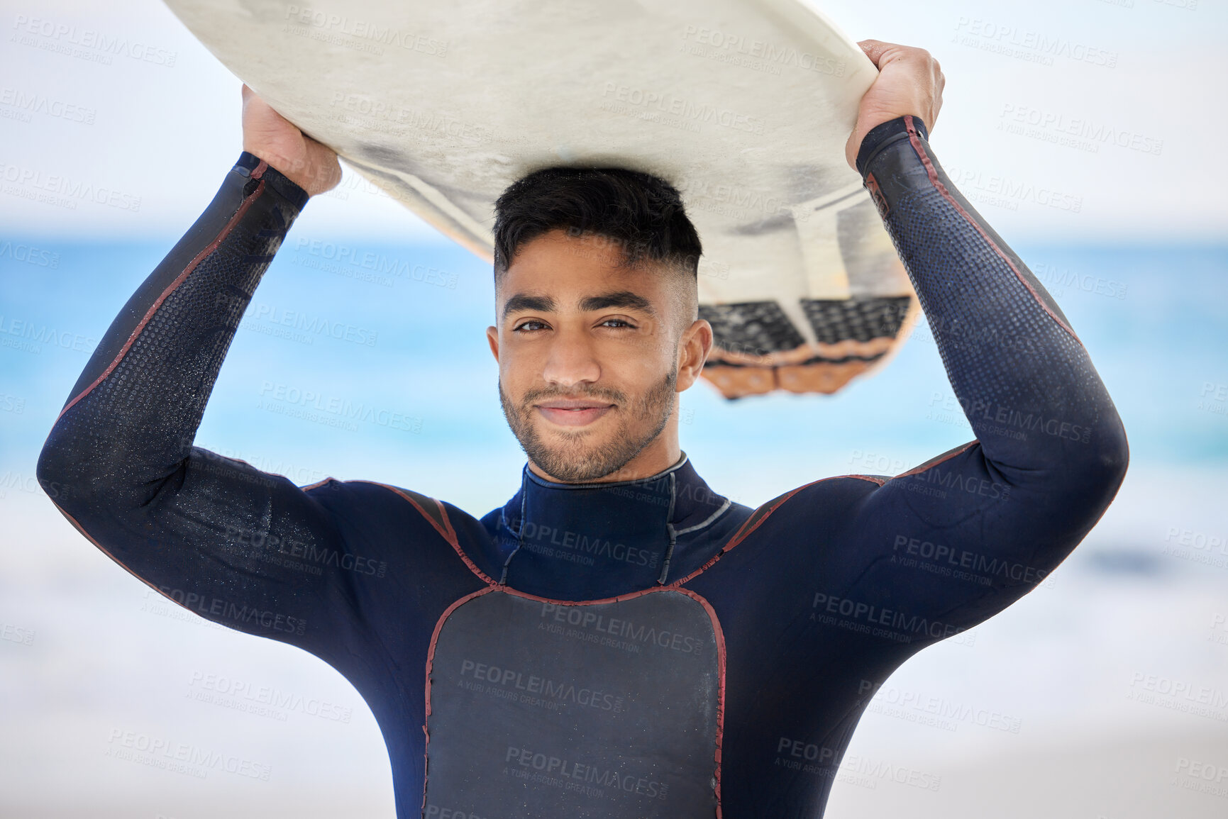 Buy stock photo Shot of a young man holding a surfboard at the beach