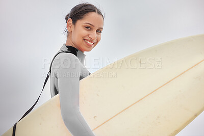 Buy stock photo Shot of a young woman holding a surfboard at the beach