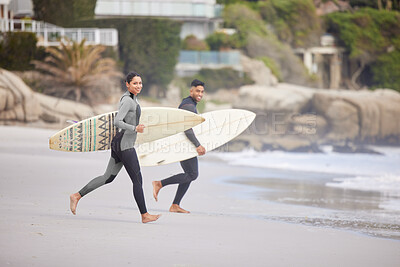 Buy stock photo Shot of a young couple running into the water with surfboards at the beach
