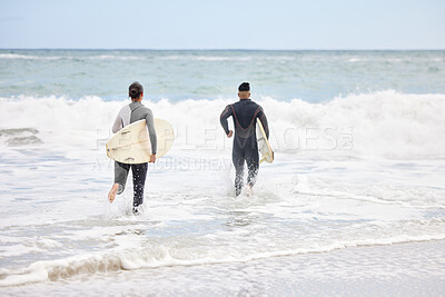 Buy stock photo Shot of an unrecognizable couple running into the water with surfboards at the beach