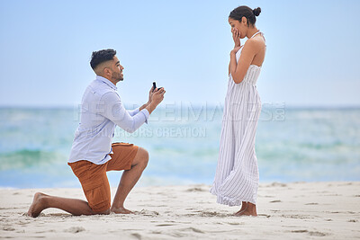 Buy stock photo Shot of a young man proposing to his girlfriend on the beach