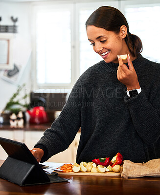 Buy stock photo Shot of a young woman chopping vegetables while watching a video recipe