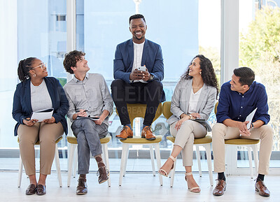 Buy stock photo Portrait of a young businessman sitting on a chair alongside candidates in an office