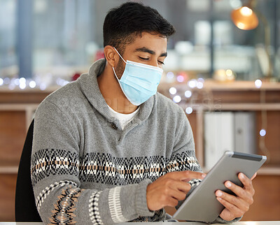 Buy stock photo Shot of a man wearing a mask and using a digital tablet