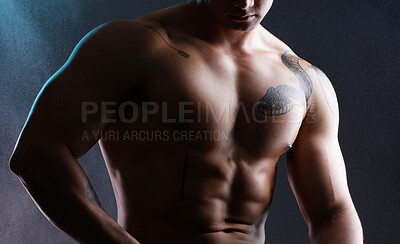 Buy stock photo Shot of an athletic young man posing shirtless against a dark background