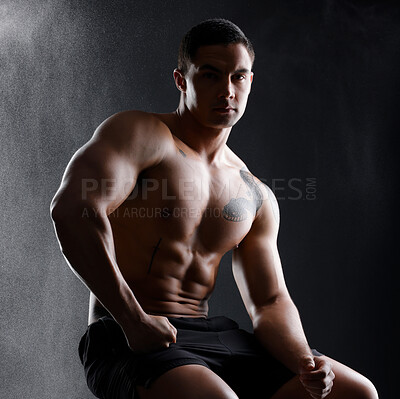 Buy stock photo Shot of an athletic young man posing shirtless against a dark background