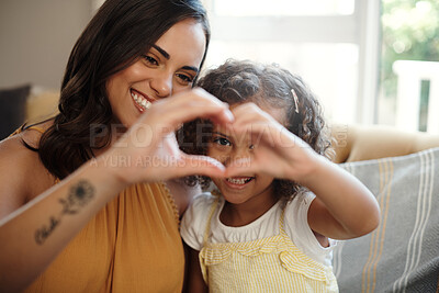 Buy stock photo Shot of an attractive woman bonding with her daughter at home and making a heart-shaped gesture