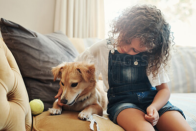 Buy stock photo Shot of an adorable young girl sitting on the sofa at home and bonding with her dog