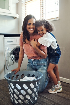 Buy stock photo Full length shot of an adorable young girl hugging her mother while helping her with the laundry at home