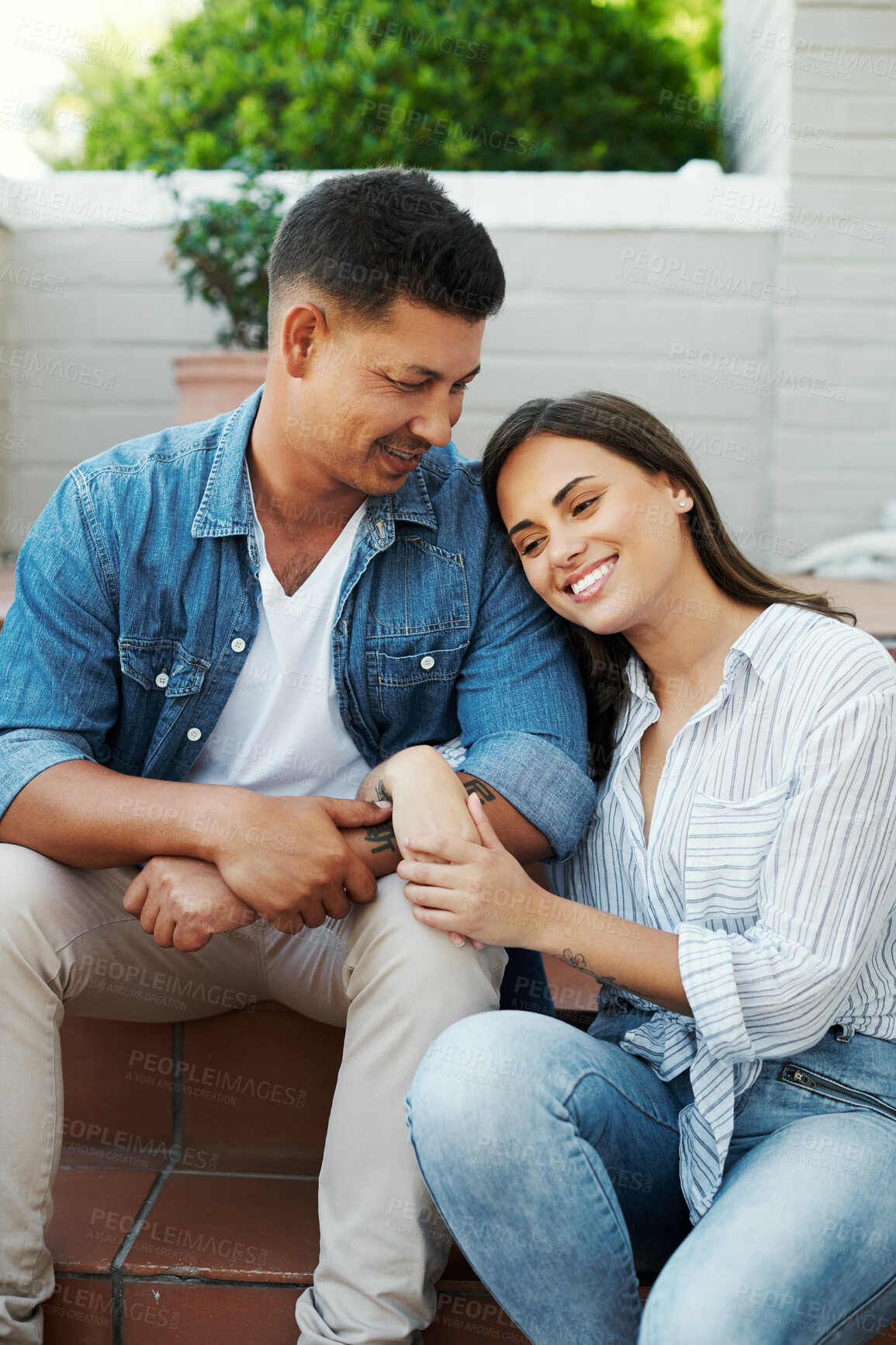 Buy stock photo Cropped shot of an affectionate young couple sitting outside on their patio in the yard