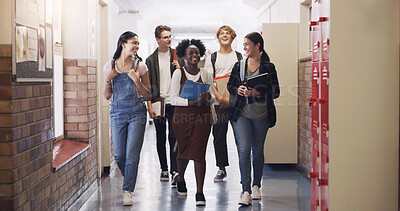 Buy stock photo Shot of a group of teenagers walking down the hall at high school