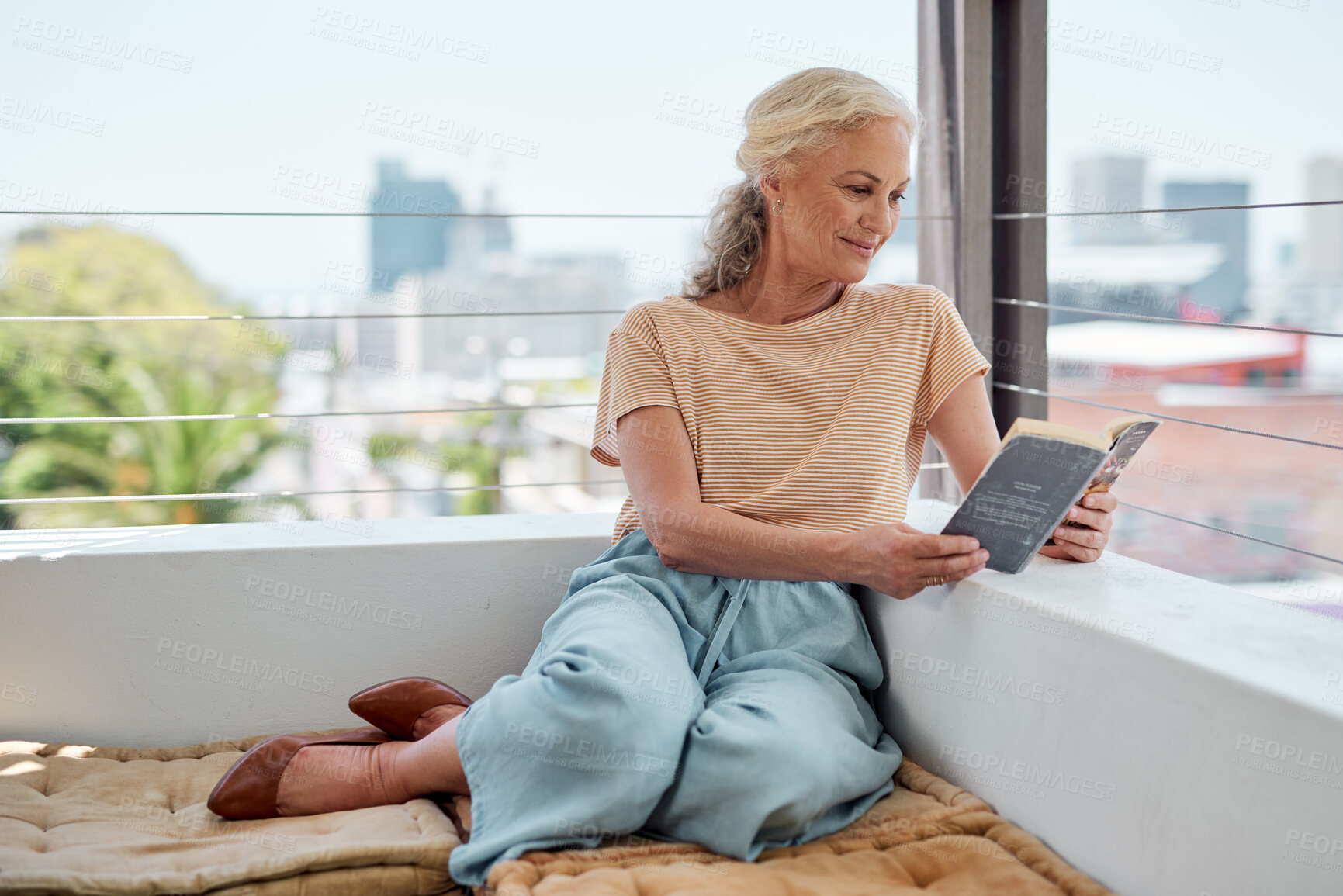 Buy stock photo Senior woman, relax and reading on balcony for retirement, book and peace in apartment. Mature, female person and novel in morning or home for calm or zen, knowledge and smile for story or fantasy