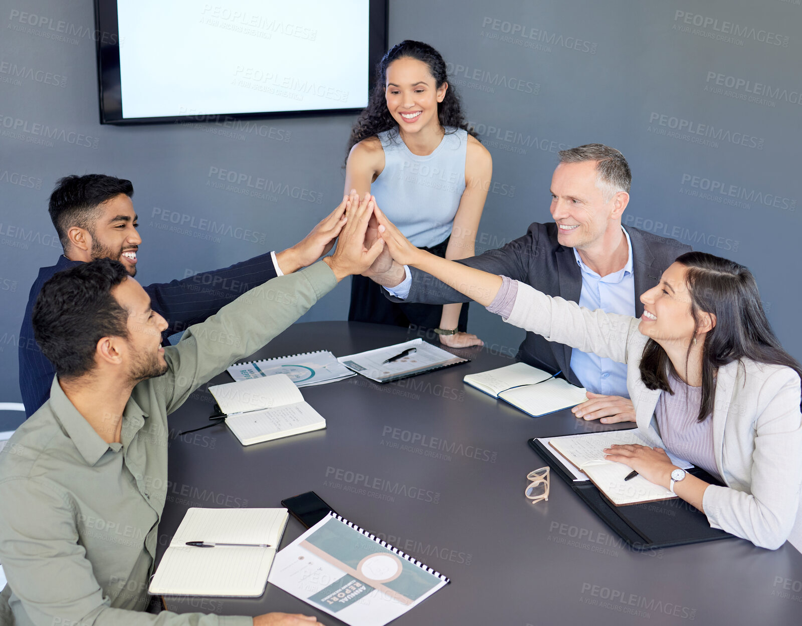 Buy stock photo Shot of a group of businesspeople giving each other a high five during a meeting in an office