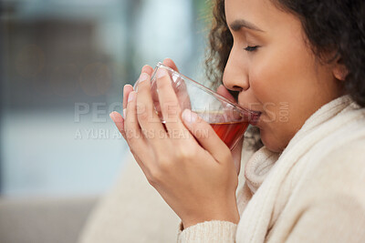 Buy stock photo Cropped shot of an attractive young woman drinking a glass of herbal tea while sitting on a sofa at home