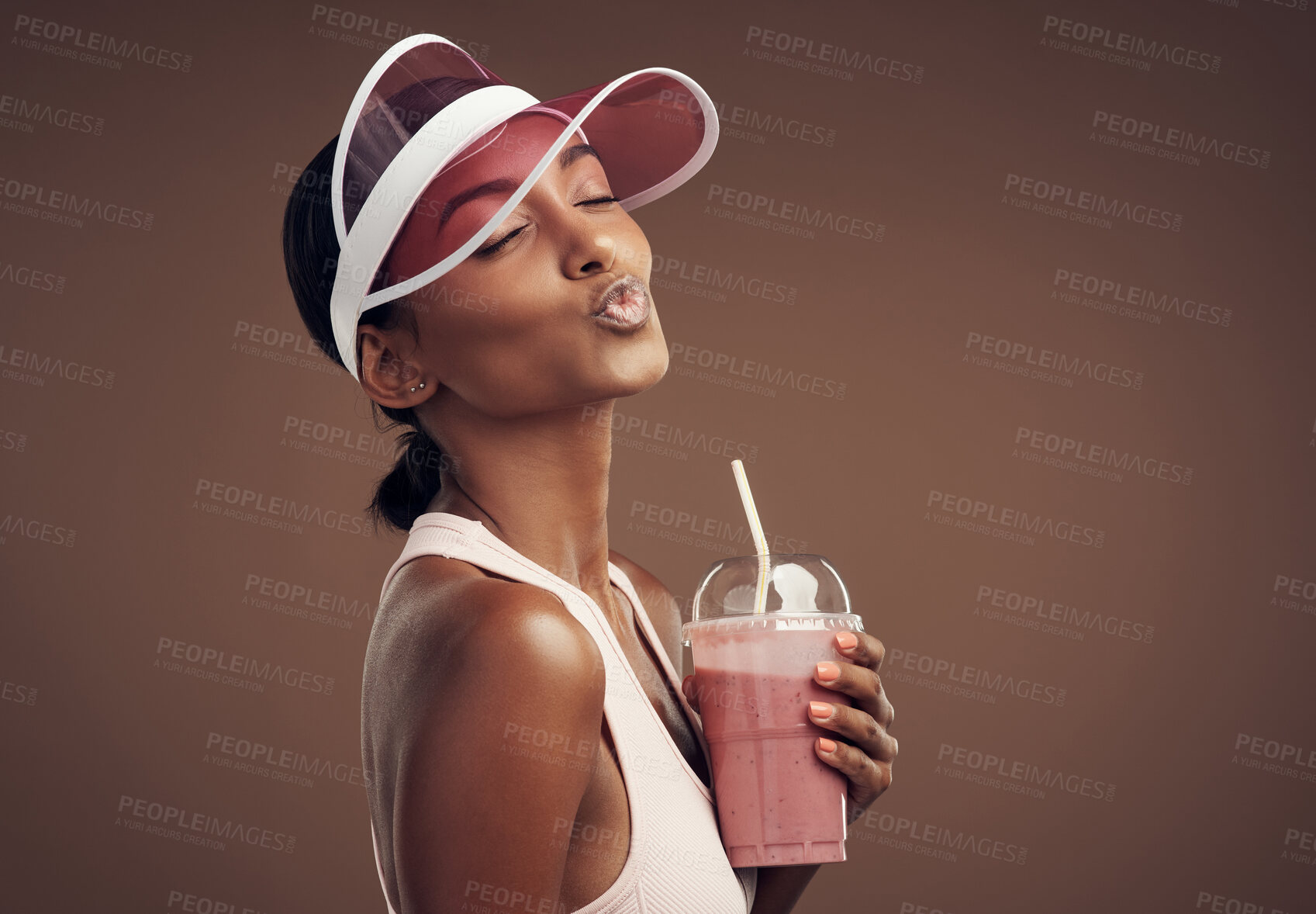 Buy stock photo Shot of an attractive young woman standing alone in the studio and feeling playful while enjoying a smoothie