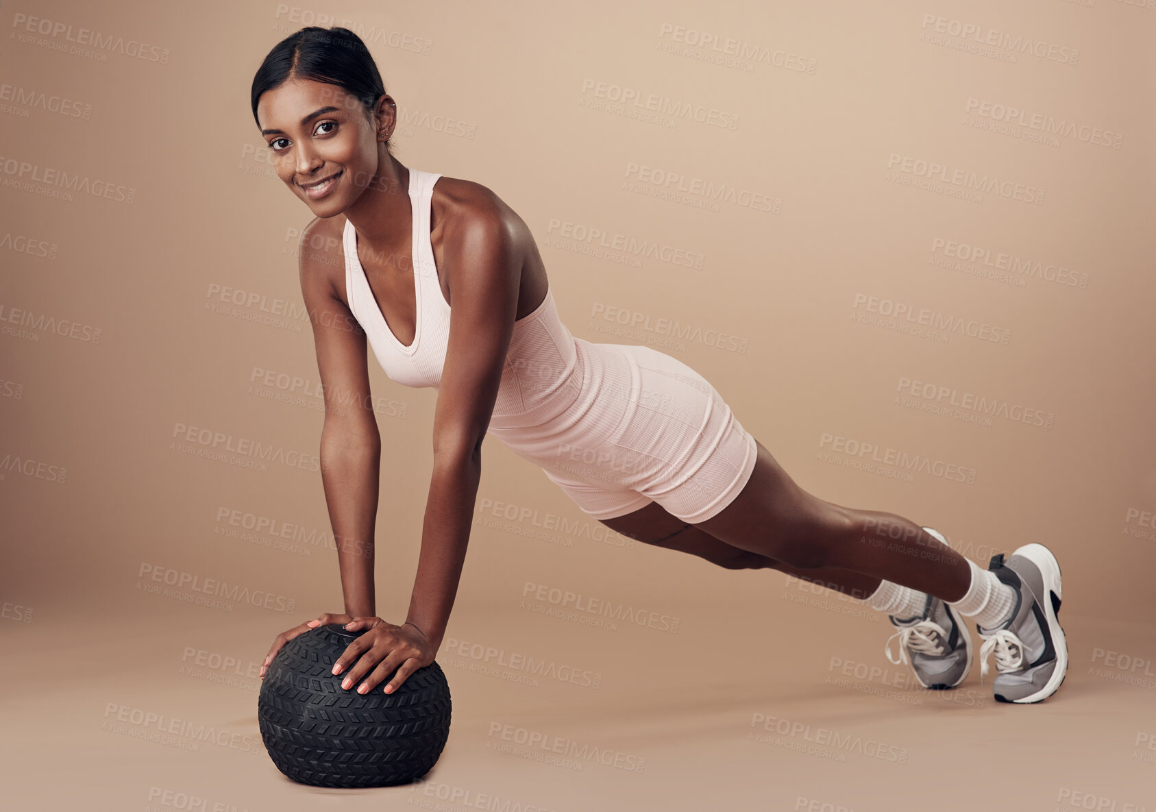 Buy stock photo Full length shot of an attractive young woman working out in the studio and using a medicine ball while doing pushups