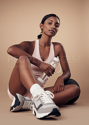Buy stock photo Full length shot of an attractive young woman sitting alone and posing in the studio after her workout