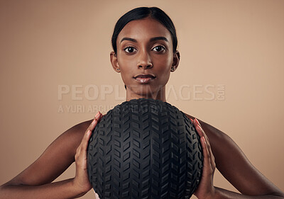 Buy stock photo Shot of an attractive young woman standing alone in the studio and holding a medicine ball while working out