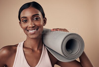Buy stock photo Shot of an attractive young woman standing alone in the studio and holding a yoga mat