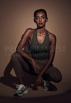 Buy stock photo Full length shot of an attractive young woman crouching down and posing in the studio after her workout