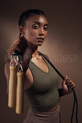 Buy stock photo Shot of an attractive young woman standing alone in the studio and posing with a skipping rope before working out