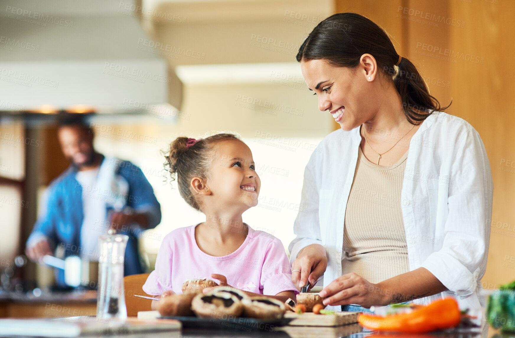 Buy stock photo Shot of a little girl assisting her mother with chopping vegetables at home