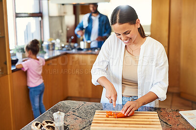 Buy stock photo Shot of a young woman chopping carrots at home