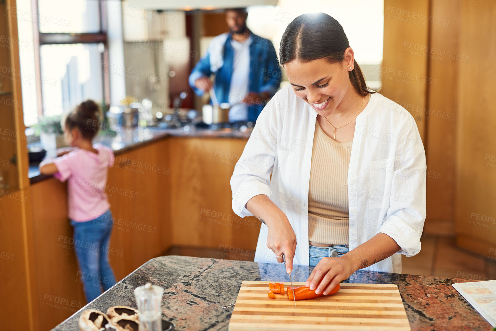 Buy stock photo Shot of a young woman chopping carrots at home