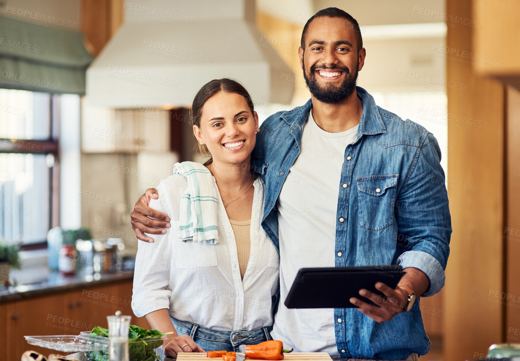 Buy stock photo Shot of a young couple using a digital tablet while cooking at home