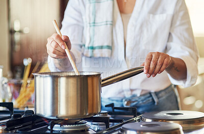 Buy stock photo Cropped shot of a young woman stirring a pot in her kitchen at home