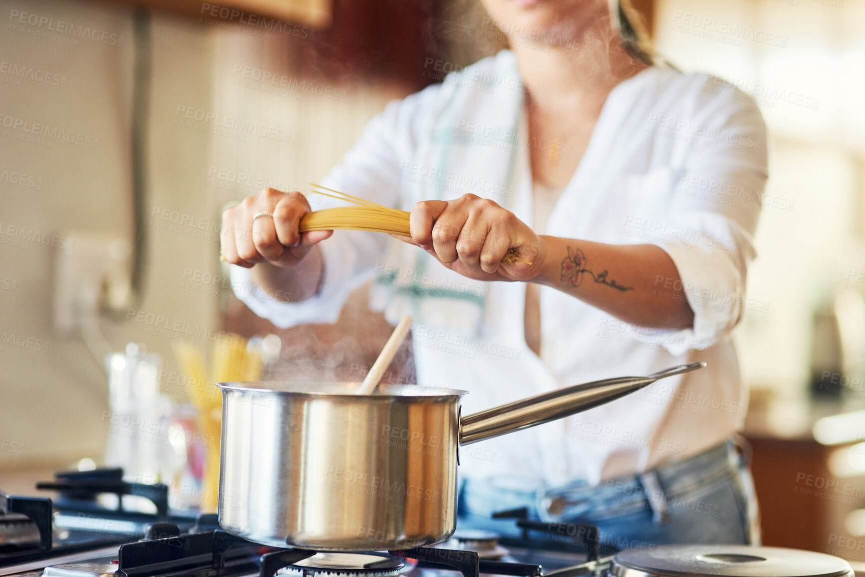 Buy stock photo Shot of a woman breaking spaghetti before boiling it