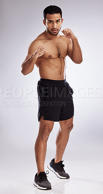 Buy stock photo Shot of a young man practicing his punches against a studio background