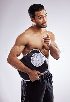 Buy stock photo Pointing, portrait and man with scale for fitness in studio for body care, wellness and diet for muscles. Male person, athlete or bodybuilder and smile for weight loss or exercise by white background