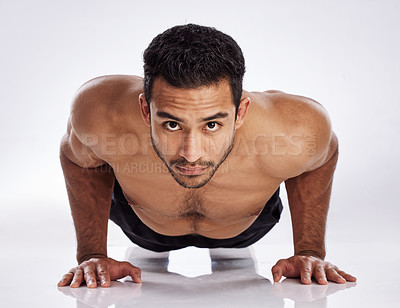 Buy stock photo Shot of a young man practicing push ups against a studio background