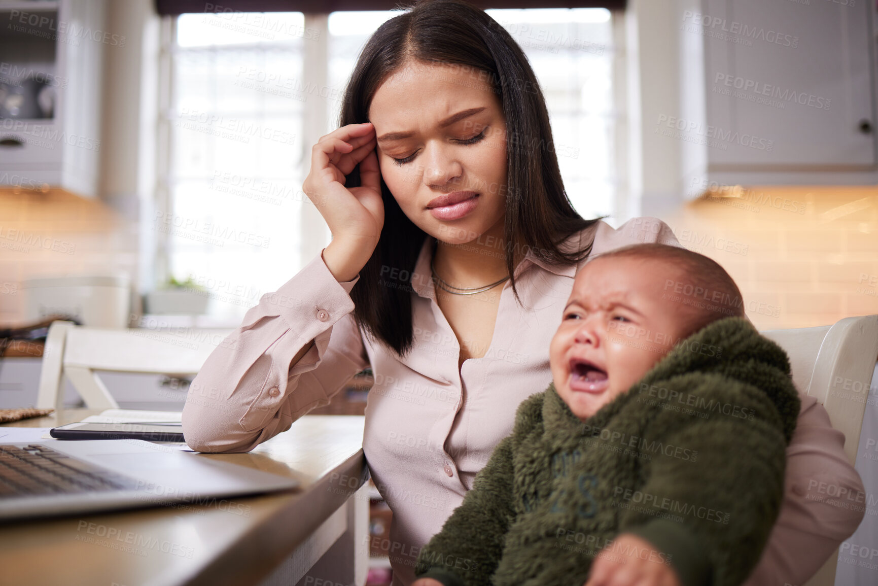 Buy stock photo Shot of a young woman using a laptop while caring for her adorable baby at home