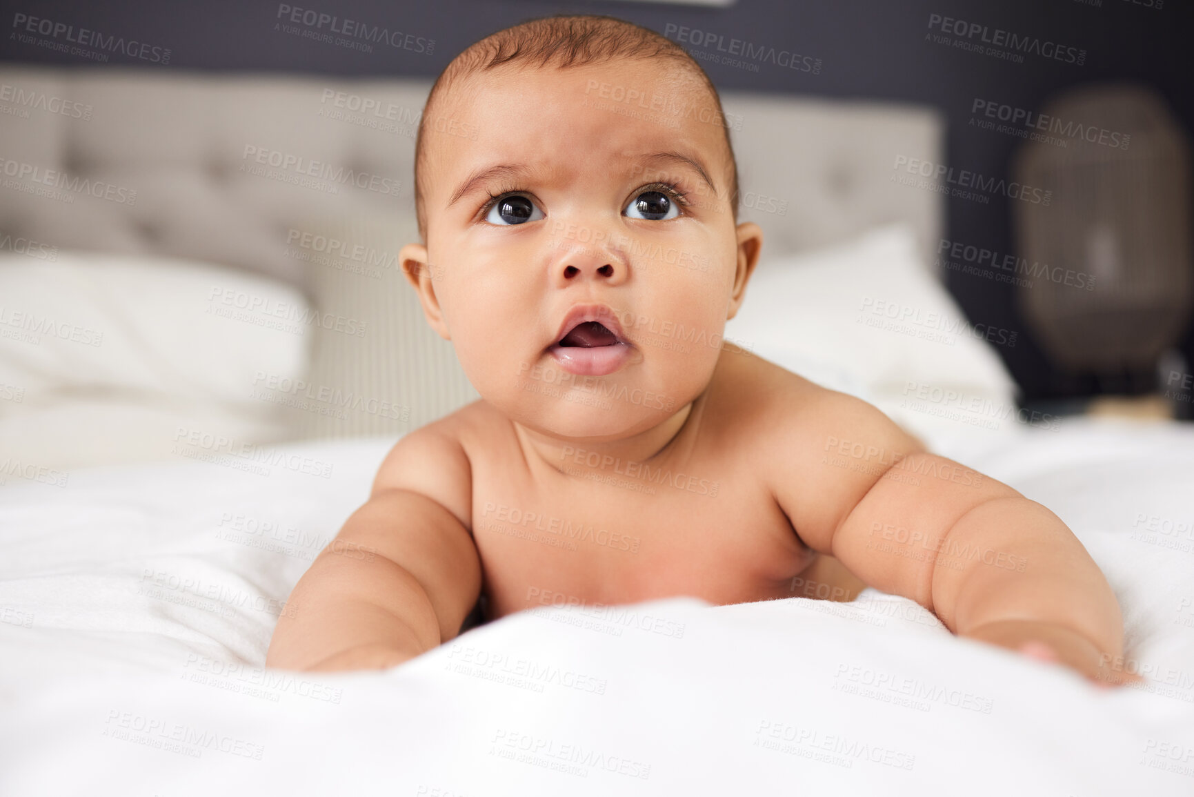 Buy stock photo Baby, relax and surprised on bed in home with morning routine, tummy time or waking up. Wellness, curious infant and resting in bedroom for sensory development, child care and getting ready in house