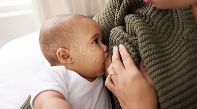 Buy stock photo Shot of a young woman breastfeeding her adorable baby on the sofa at home