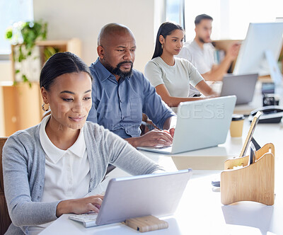 Buy stock photo Shot of a group of businesspeople working on laptops in an office