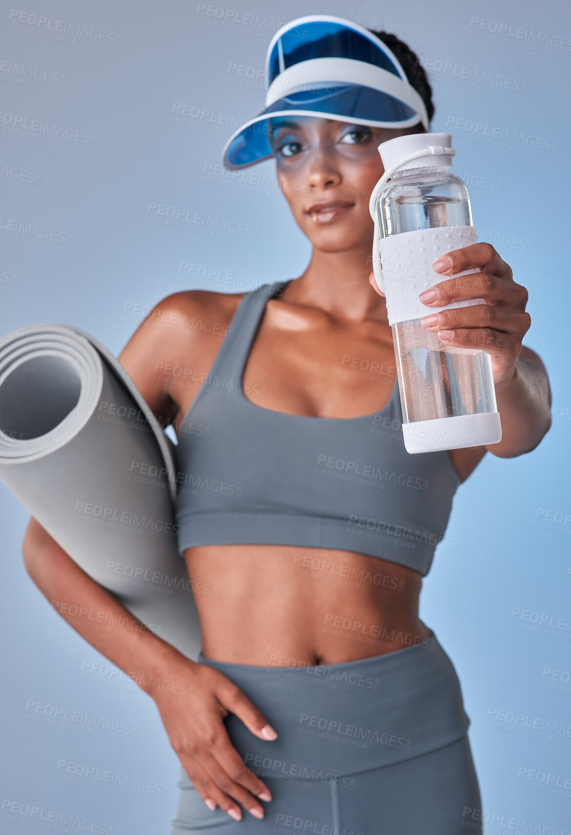 Buy stock photo Studio shot of a fit young woman drinking bottled water against a grey background