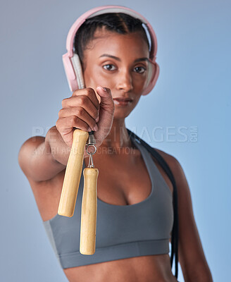Buy stock photo Studio shot of a fit young woman working out with jump rope against a grey background