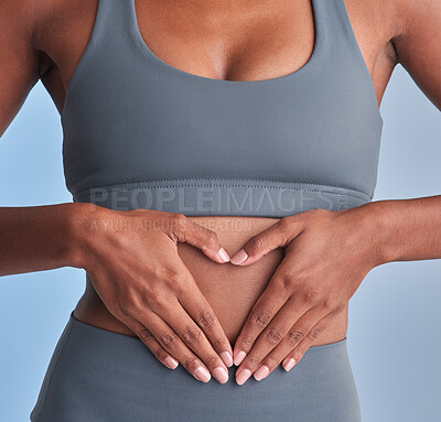 Buy stock photo Studio shot of a fit woman making a heart shaped gesture over her stomach against a grey background