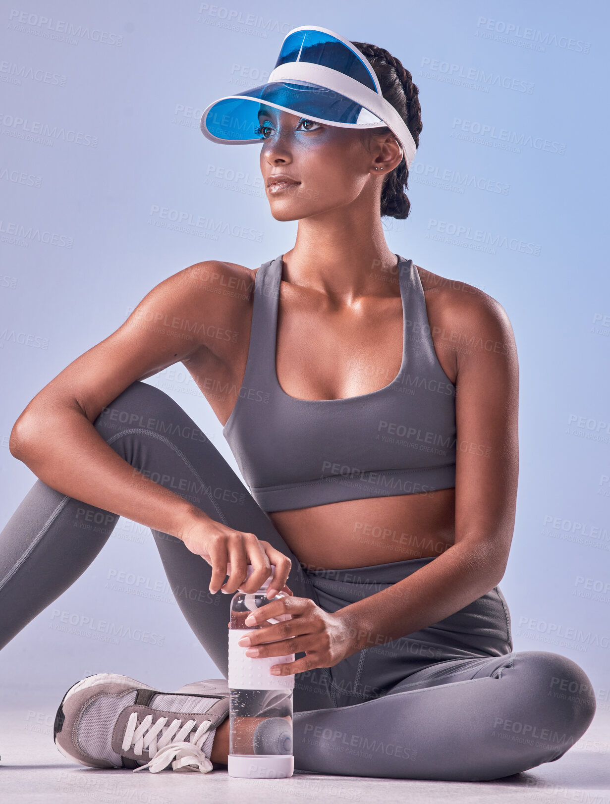 Buy stock photo Studio shot of a fit young woman drinking bottled water against a grey background